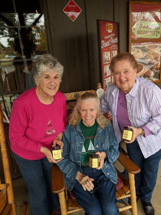 Three women smiling and holding jars of RedGold