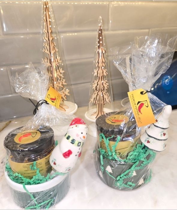 Two RedGold crock sets wrapped in cellophane, one with a snowman spreader and one with a Christmas-tree spreader