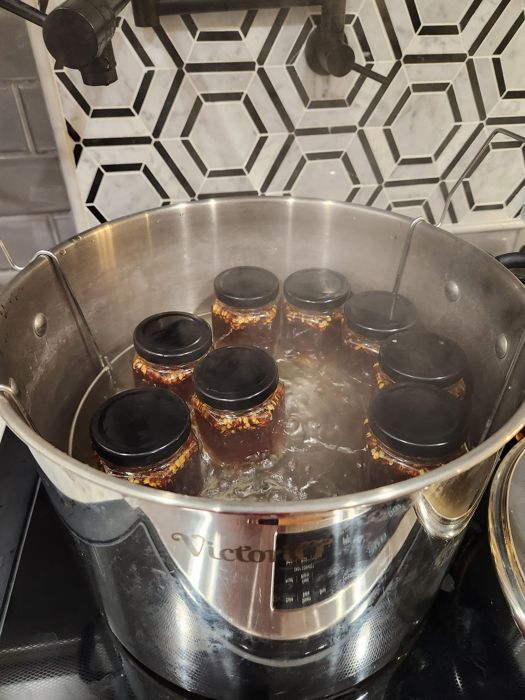 Jars of pepper jelly in a pot of water on the stove